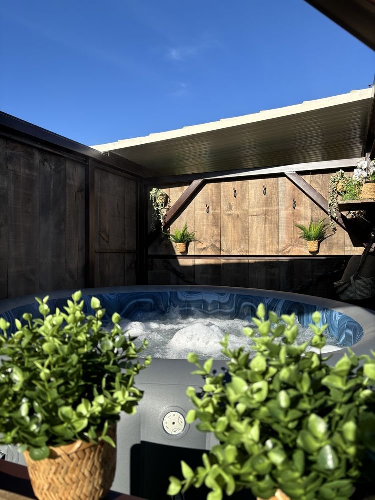 The hot tub in its wooden cabin, surrounded by plants