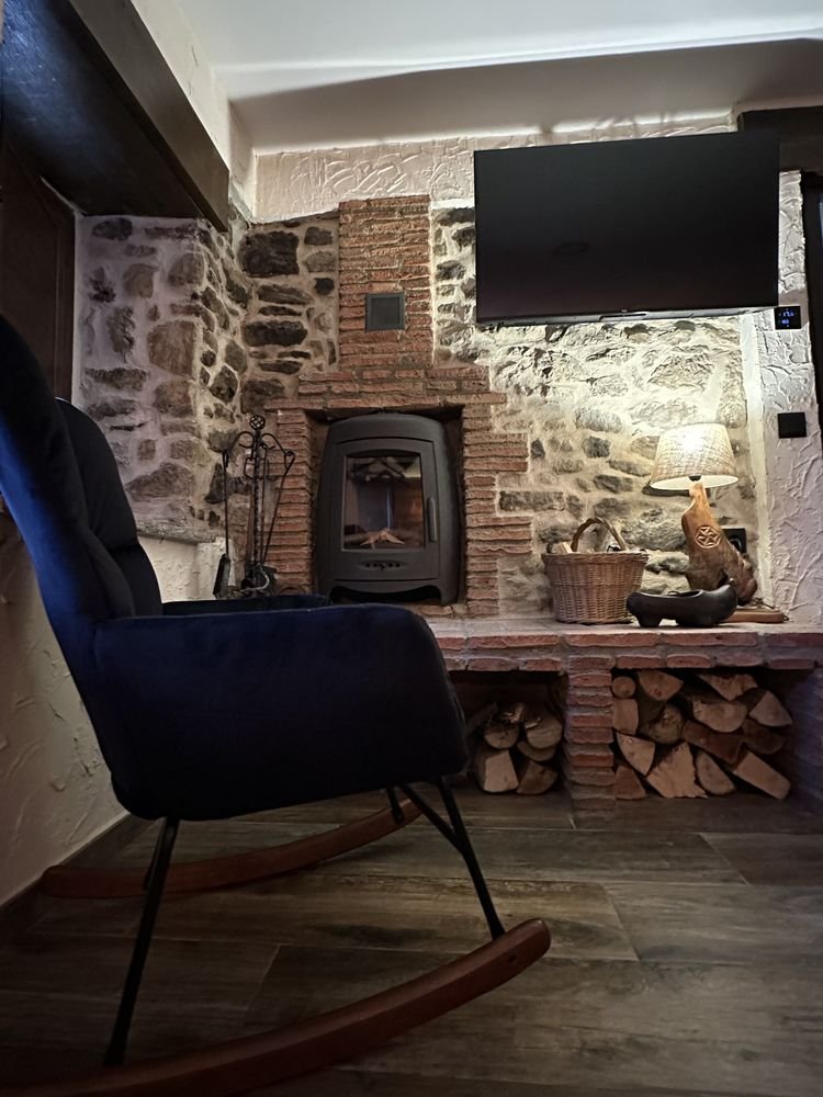 Corner with a wood-burning fireplace, stone wall and rocking chair