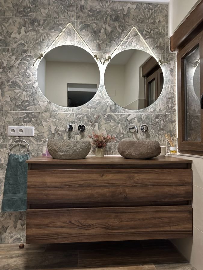 Bathroom with two stone basins and illuminated mirrors