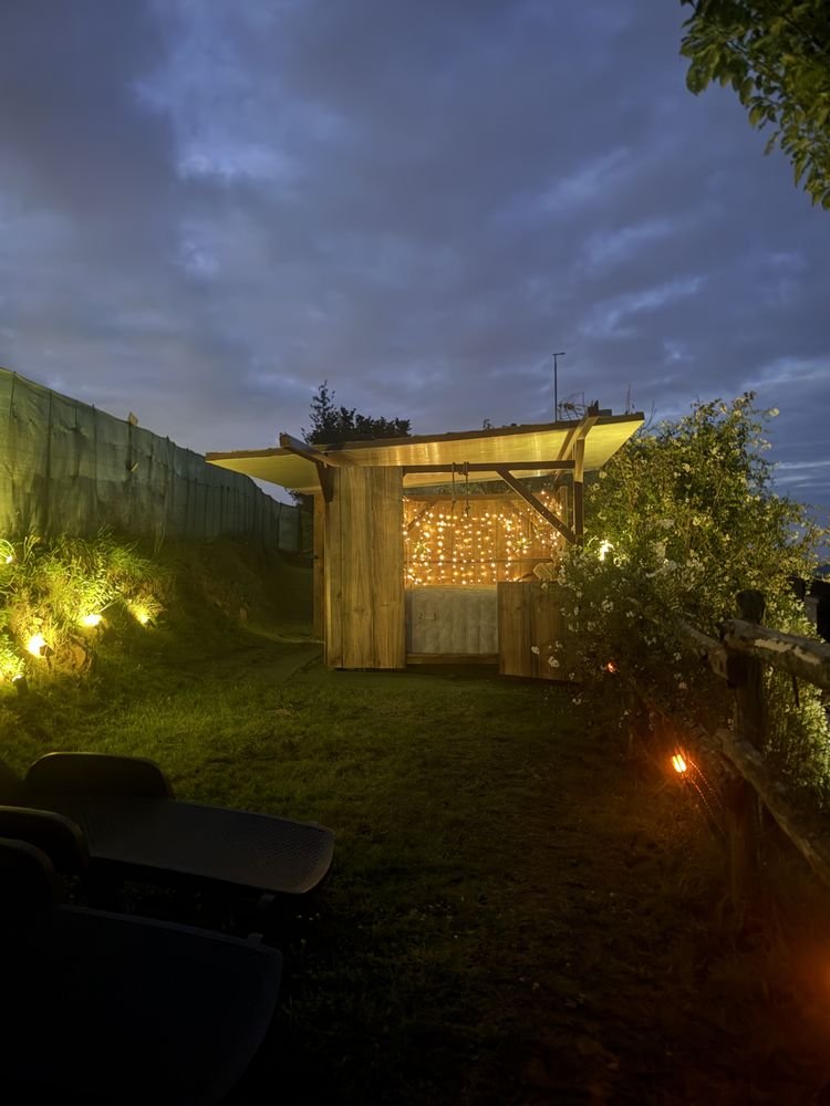 The garden lit up at night, with the hot tub cabin