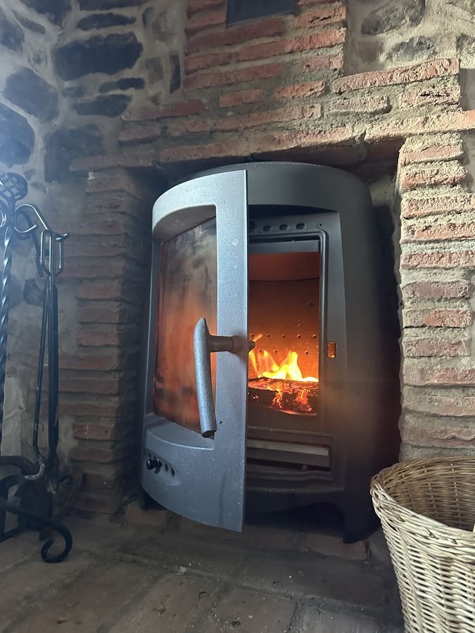 Wood-burning stove alight in a brick and stone wall