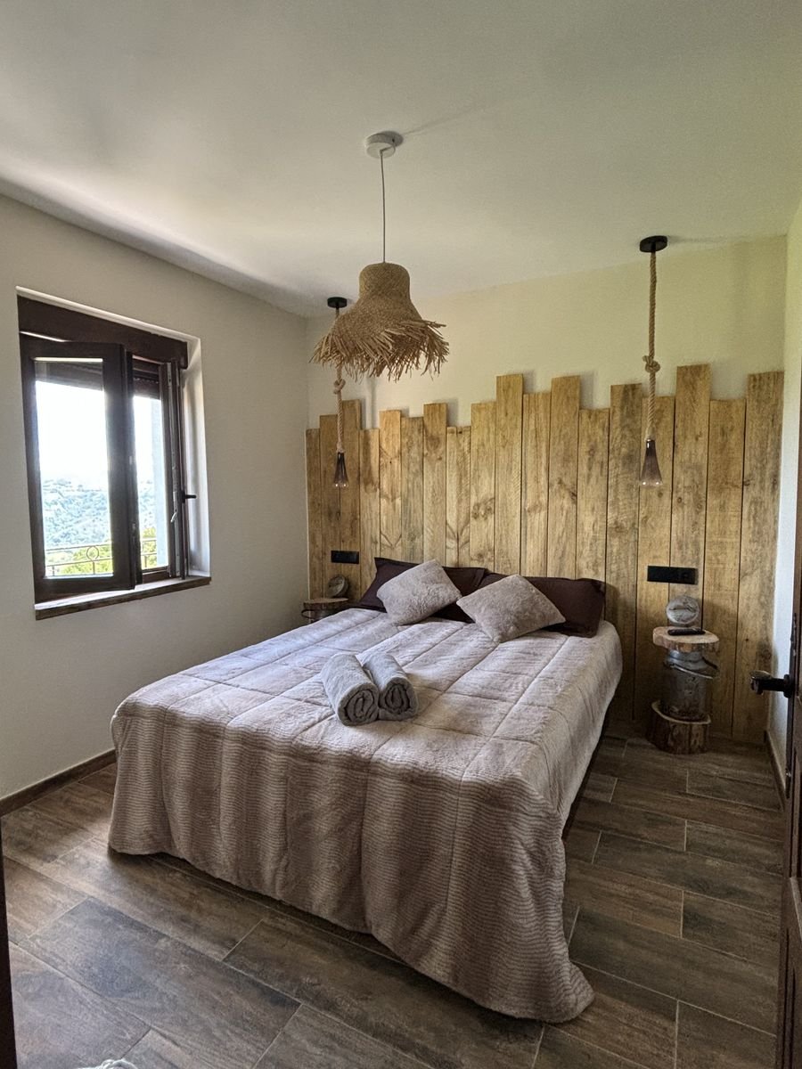 Bedroom with a wooden plank headboard and a woven pendant lamp