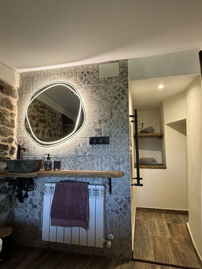 Bathroom with a stone basin and illuminated mirror