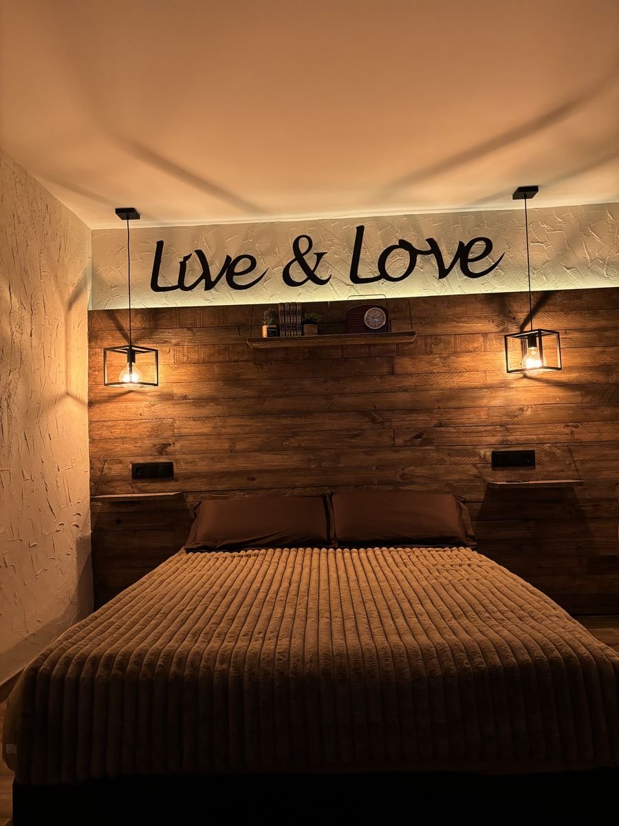 Bedroom with a wooden wall, iron lamps and the Live and Love sign