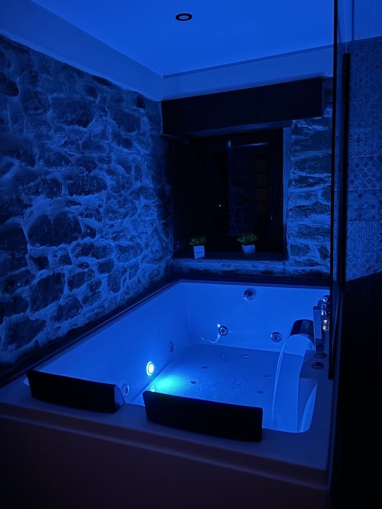 Whirlpool bath for two with blue lighting and a stone wall