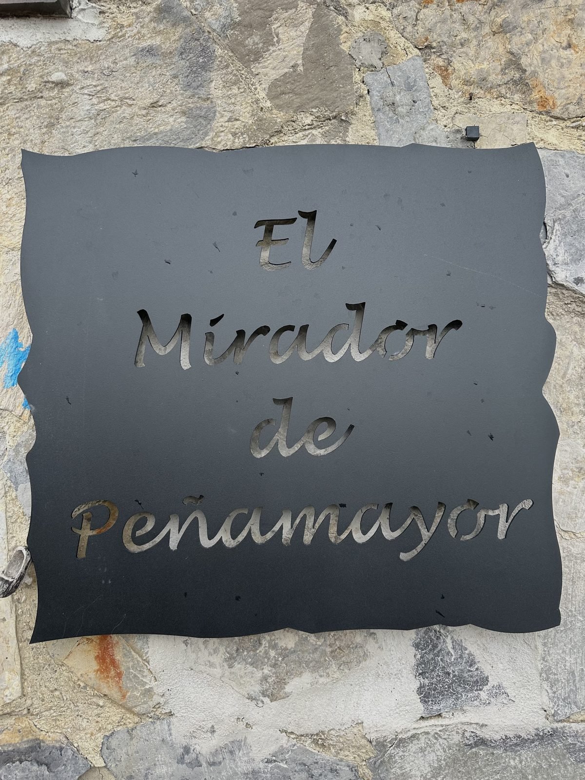 Iron sign for El Mirador de Peñamayor on the stone wall
